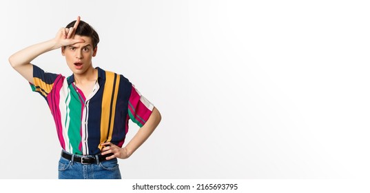 Sassy And Arrogant Guy Showing Loser Sign On Forehead, Mocking Someone, Standing Over White Background