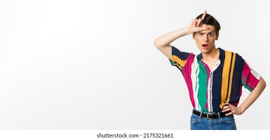 Sassy And Arrogant Guy Showing Loser Sign On Forehead, Mocking Someone, Standing Over White Background