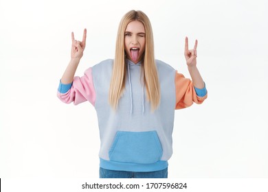 Sassy And Rebellious Teen Girl Having Fun On Awesome Party, Showing Tongue And Wink, Make Rock-n-roll, Heavy Metal Sign, Enjoying Cool Music Concert, Standing White Background