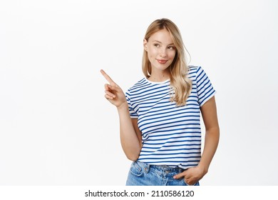 Sassy Young Blond Woman Shaking Finger, Pointing Left With Smug Face, Showing Announcement Or Advertisement, White Background