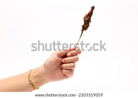 satay in woman's hand isolated on white background. Indonesian traditional food. Indonesian dish.