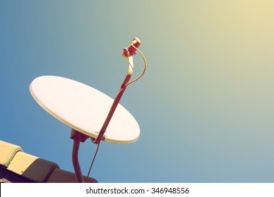 satellite dish and TV antennas on the house roof with blue sky background