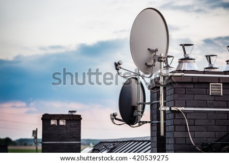 Satellite dishes, satellite antennas mounted on the chimney of a new home. Evening