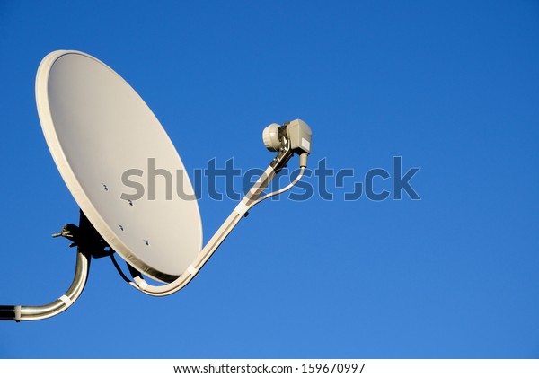 Satellite TV antenna on\
blue sky background