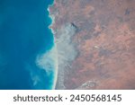 Satellite view of Eighty Mile Beach and Lagrange, Western Australia, with red desert and a plume from a volcano over the turquoise Indian Ocean. Elements of this image furnished by NASA