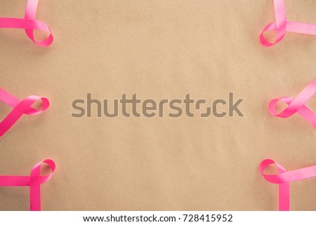 Satin pink ribbons, supporting symbol of breast cancer awareness campaign in October, on light brown paper background border design with copy space