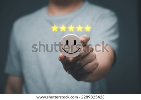 Satisfaction concept, Five-star rating and smiley face icon by male customers or the highest satisfaction, Man holding circular wooden board with smiling face icon.