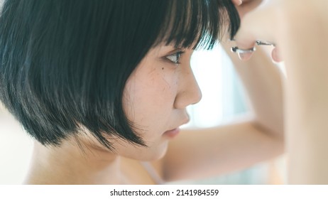 Satisfaction Lifestyle Stay At Home Concept. Young Adult Authentic Asian Woman Self Cutting Bangs Haircut With Scissors. Background On Day With Nature Light.