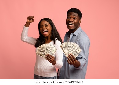 Satisfied African American Millennial Couple Holding Bunch Of Money Banknotes And Celebrating, Raising Hands Up And Screaming, Pink Studio Background, Lucky Black Man And Woman Won Lottery