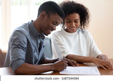 Satisfied African ethnicity couple affirming prenuptial contract, smiling husband putting signature on lease agreement, young family taking loan in bank filling form, health insurance buyers concept