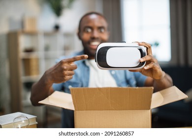 Satisfied African Man Opening Parcel Box With New VR Glasses While Sitting At Home. Male Blogger Talking On Camera While Doing Reviews For Subscribers.