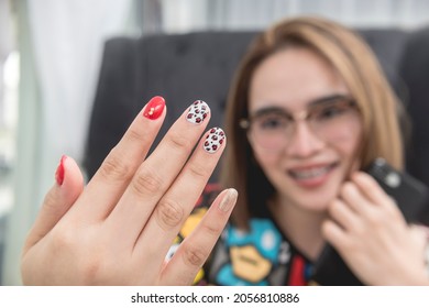 A Satisfied Asian Woman Proudly Shows Her Newly Manicured Nails With Mixed Nail Art Designs. At A Beauty Parlor Or Salon.