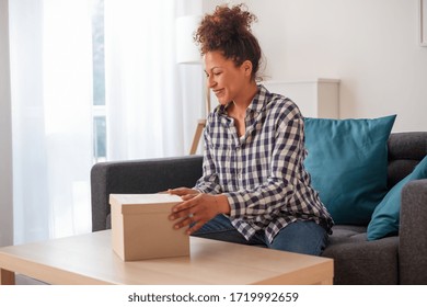Satisfied black woman unboxing just delivered item after home shopping