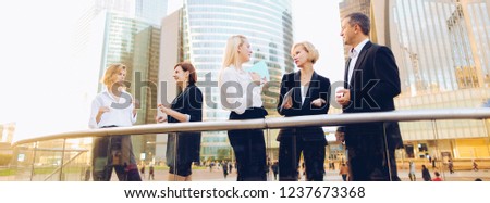 Satisfied business team members speaking outdoors in  . Concept of biz partners enjoying successful result. Businesswomen talking with male boss and smiling.