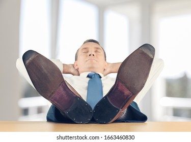 Zufriedener Geschäftsmann im komfortablen Bürostuhl während der Pause