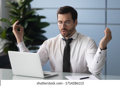 Satisfied Businessman Relaxing, Meditating In Yoga Pose Breathing Exercises At Workplace. Mindful Employee Sitting At Office Desk With Laptop, Stress Relief, Emotion Control Concept.