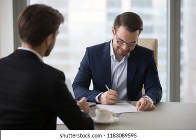 Satisfied businessman sign contract after successful negotiation or meeting with business partner, happy male CEO put signature on document closing deal with work associate. Partnership concept - Shutterstock ID 1183089595