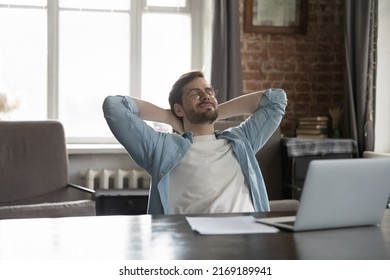 Satisfied by work done employee put hands behind head breath fresh-conditioned air looks carefree sit at workplace desk with laptop enjoy comfort break, relax alone in modern office. No stress concept