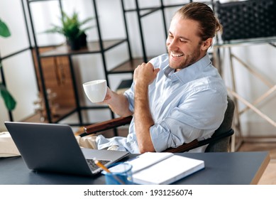 Satisfied caucasian successful guy, freelancer or ceo, relaxes at workplace with legs thrown on table. Stylish guy uses laptop, browses the Internet, looks for ideas for a project, sitting at the desk