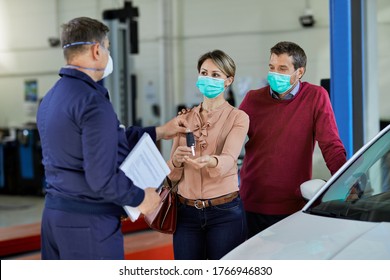 Satisfied Customers Receiving Their Car Key From Auto Repairman In A Workshop. 