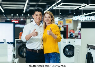 Satisfied Diverse Couple Of Shoppers Asian Man And Woman Smiling And Looking At Camera, Satisfied And Positive And Recommending Store Hold Thumbs Up, Shoppers In Electronics Store