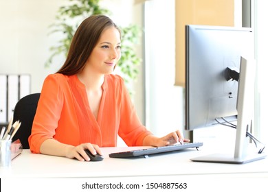 Satisfied entrepreneur in orange working with desktop computer at office - Powered by Shutterstock