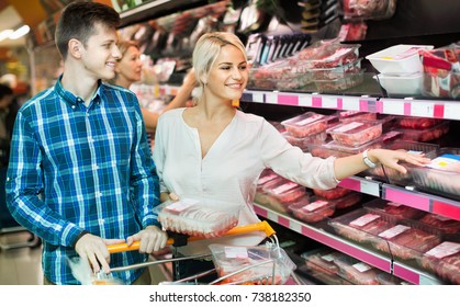 Satisfied family couple choosing chilled meat in food store
