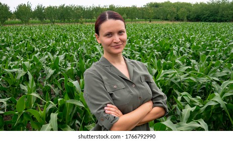 Satisfied female farmer with arms crossed in a corn field. Woman in agriculture business.