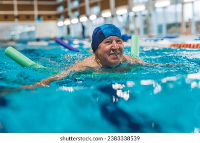 satisfied and happy aged man swimming with a noodle in the indoor pool. High quality photo