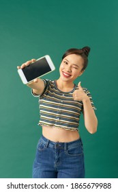 Satisfied Happy Asian Girl Show Thumbs-up As Demonstrate Mobile Phone Screen Application, Standing Green Background Recommend App