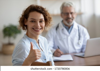 Satisfied Healthy Smiling Young Adult Woman Patient Looking At Camera Sitting At Old Doctor Consultation Showing Thumbs Up Recommend Good Quality Women Healthcare Medical Services Concept. Portrait.