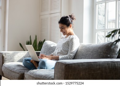 Satisfied Indian woman relaxing on comfortable couch, using laptop at home, happy girl chatting with friends in social network, spending lazy weekend, watching movie, shopping online, writing email - Shutterstock ID 1529775224