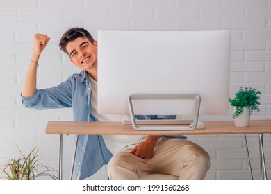 satisfied male teenage student at desk with computer
