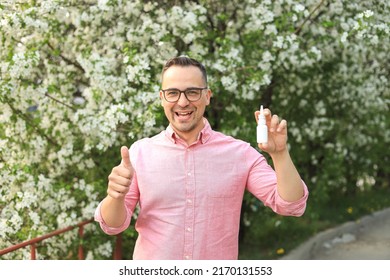 Satisfied Man With Nose Spray Against The Background Of Flowering Trees