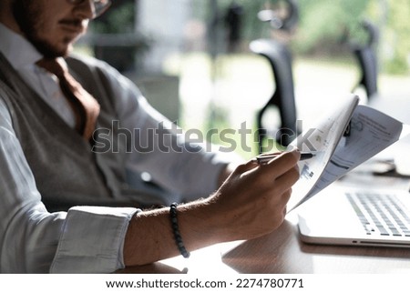 Satisfied man reading paper documents, letters, receiving pleasant news, working at workplace, sitting on desk, successful businessman, freelancer looking at contract with good offer