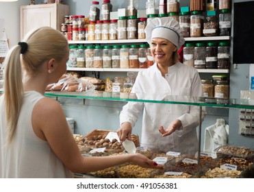 Satisfied Mature Woman Buying Different Nuts For Customer In Local Supermarket