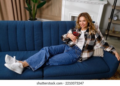 Satisfied Mature Woman Drinking Wine On The Sofa In The Living Room