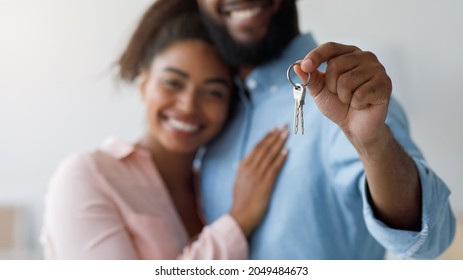 Satisfied Millennial Black Couple Hugging, Showing Keys To New Apartment. Focus On Keys To First Own House. Smiling Millennial Man And Woman Celebrate Relocation To New Home, Moving, Rental, Estate