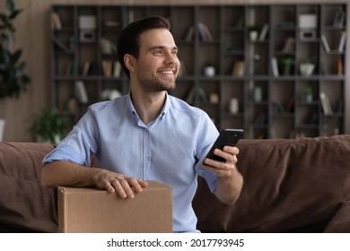 Satisfied millennial man sit on couch hold postal parcel smartphone enjoy express delivery courier service ordered by phone call. Happy young male client give positive feedback to package tracking app - Shutterstock ID 2017793945