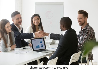 Satisfied multiracial businessmen handshaking after successful group negotiations, diverse african and caucasian partners shaking hands after signing contract at meeting promising good deal concept