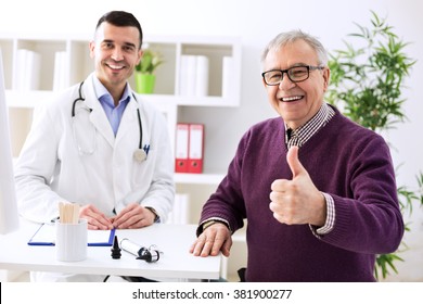 Satisfied Old Patient With Success Young Doctor In Office