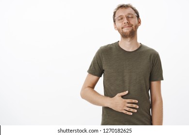 Satisfied And Pleased Male Visiting Favorite Restaurant Licking Lips And Closing Eyes Rubbing Belly From Delight And Satisfaction Feeling Stuffed After Eating Tasty Food Over White Background