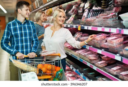 Satisfied positive family couple choosing chilled meat in food store
