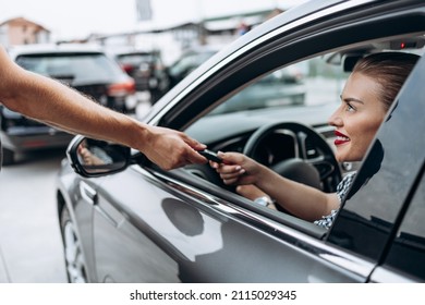 Satisfied And Smiled Female Buyer Sitting In Her New Car. She Is Smiling, Looking At Seller Through Open Window While Taking Car Keys From Him. 