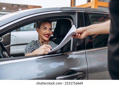 Satisfied And Smiled Female Buyer Sitting In Her New Car. She Happy While Signing Buyer's Purchase Contract With Used Car Seller.
