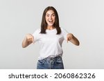 Satisfied smiling brunette girl pointing fingers down, recommend product