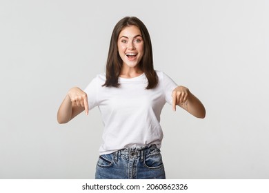 Satisfied Smiling Brunette Girl Pointing Fingers Down, Recommend Product