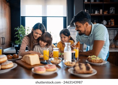 Satisfied smiling little boy spreading marmalade from jar on slice of bread for breakfast, enjoying family time with cute older sister and proud happy mother and father. - Powered by Shutterstock