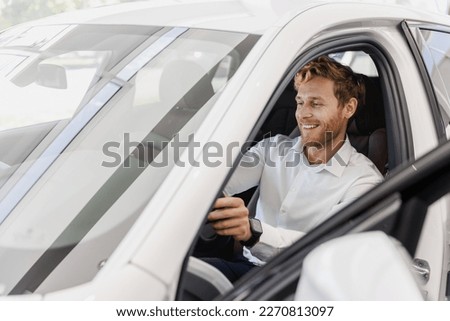 Satisfied smiling man customer buyer businessman client in classic suit sit in car salon chooses auto wants buy new automobile in showroom vehicle dealership store motor show indoor Car sales concept
