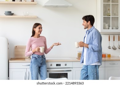 Satisfied smiling millennial woman and guy with cups of hot drink, have breakfast, talking on kitchen interior. Couple enjoying fresh delicious coffee, communication during break from work at home - Powered by Shutterstock